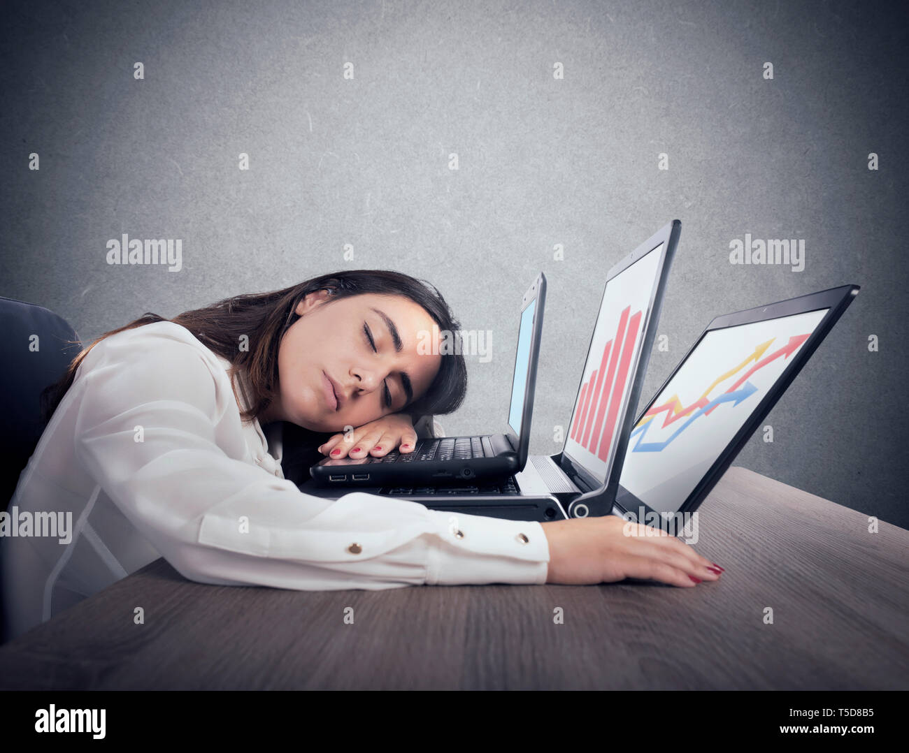 Lavoratore di sesso femminile che si addormenta lavorando simultaneamente su tre laptop Foto Stock