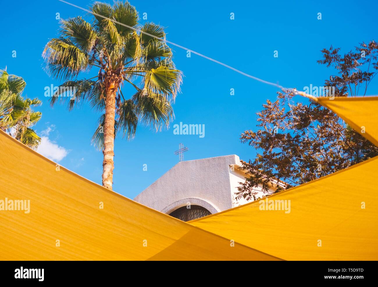 La cima della chiesa attraverso le decorazioni gialle della strada Foto Stock