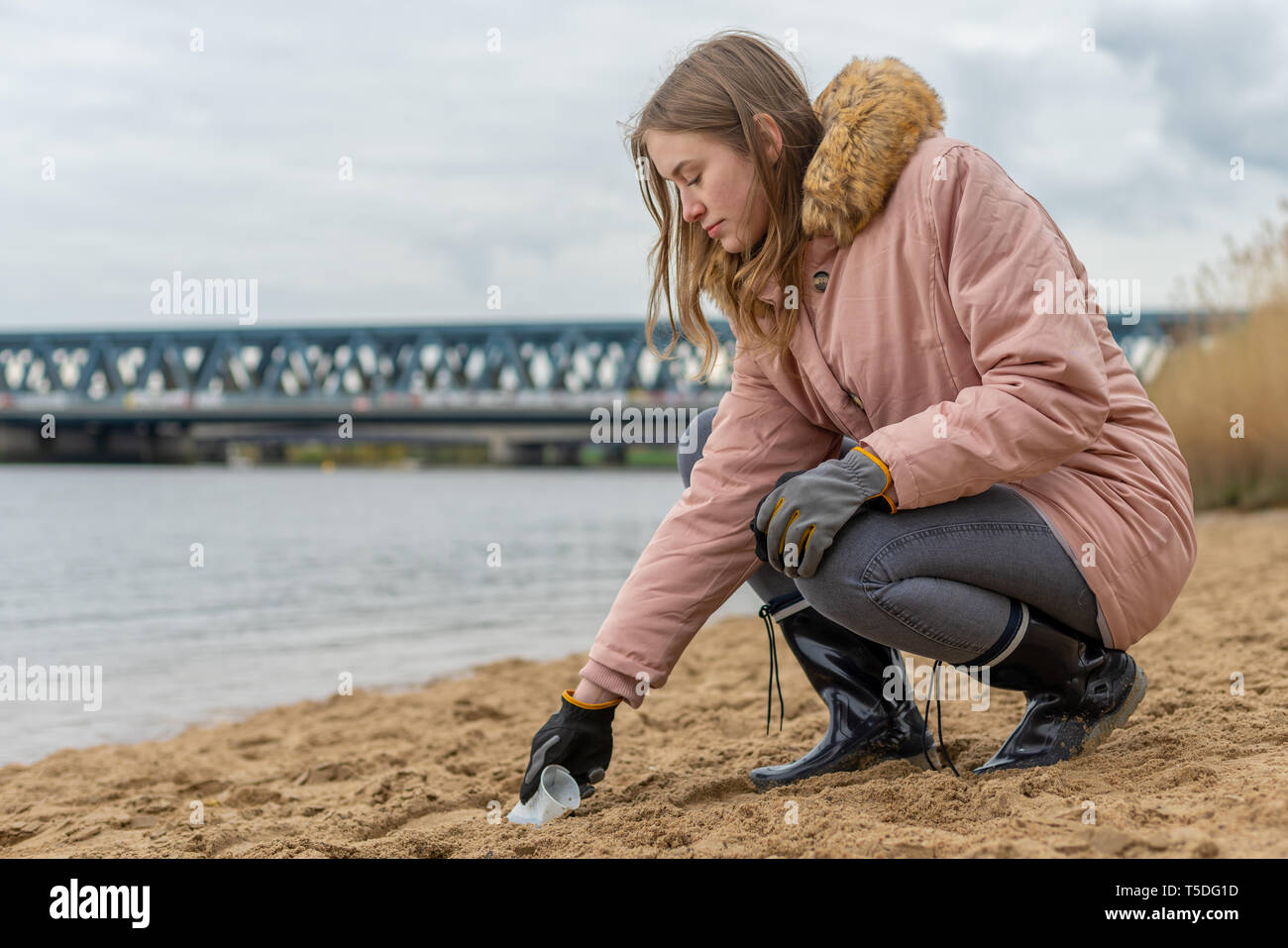 La donna è la pulizia della spiaggia da una struttura plastica rifiuti a mano Foto Stock