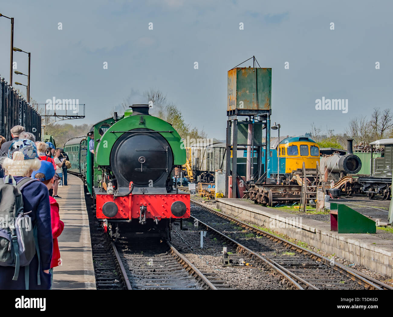 Un verde brillante treno a vapore arriva alla piattaforma per prendere il prossimo viaggio Foto Stock