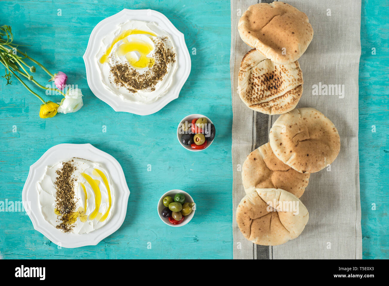 Labneh labaneh)Middle Eastern soft formaggio caprino con olio d'oliva, Za'atar, limone,pane pita ,serviti al concetto tradizionale su tavola in legno rustico Foto Stock