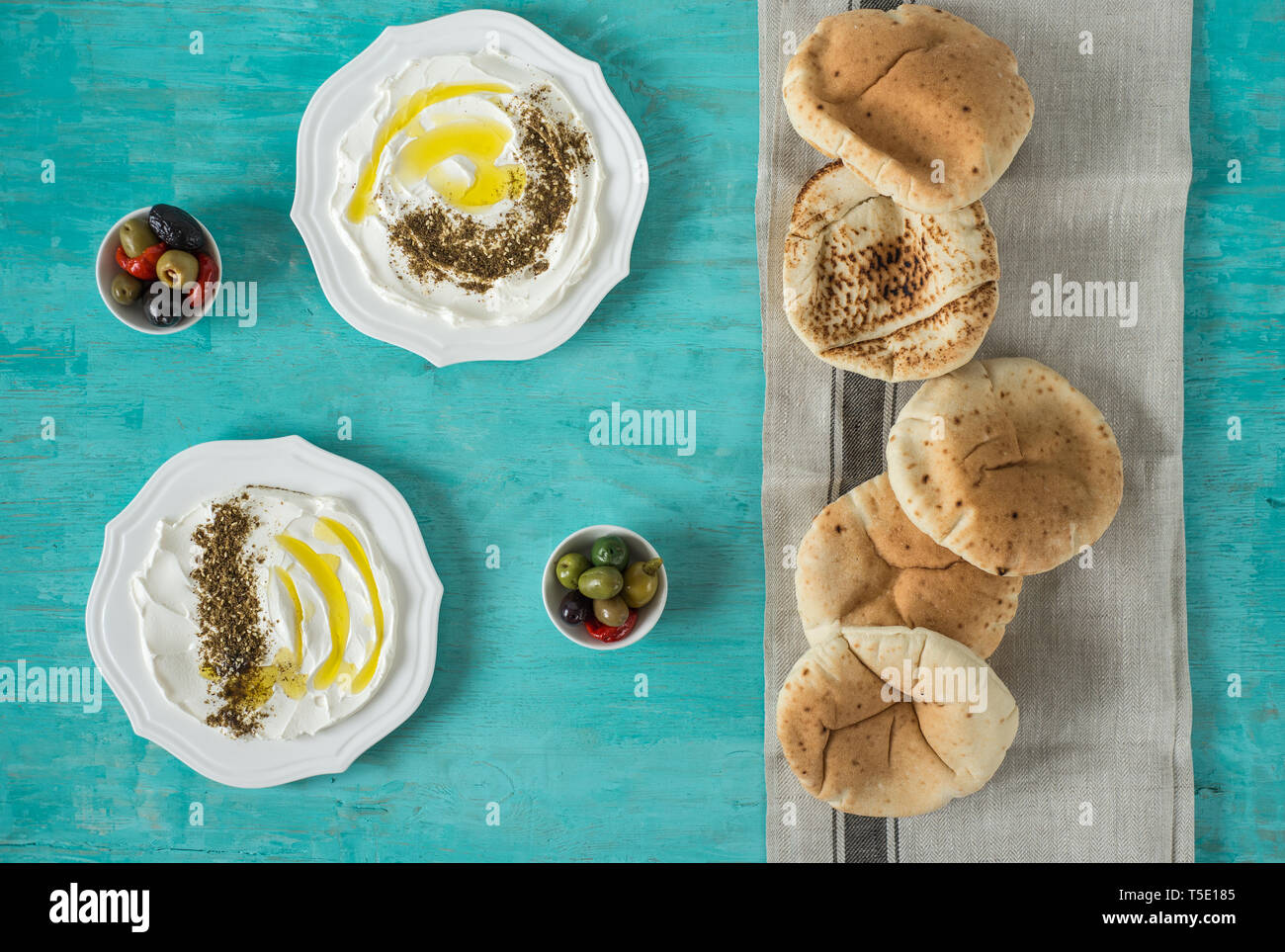 Labneh labaneh)Middle Eastern soft formaggio caprino con olio d'oliva, Za'atar, limone,pane pita ,serviti al concetto tradizionale su legno rustico tabl Foto Stock