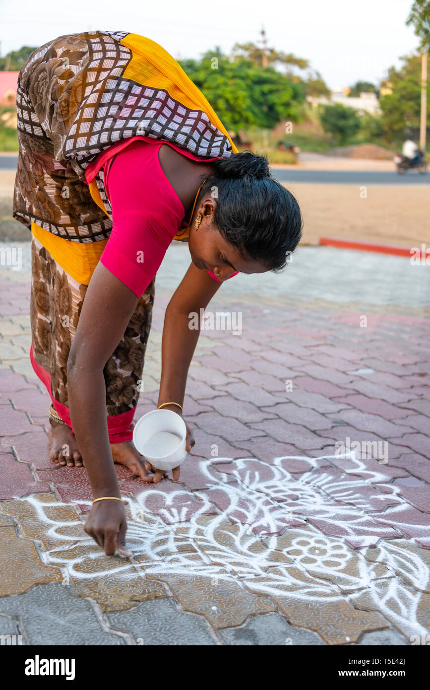 Verticale fino in prossimità di una signora disegno rangoli patterns sulla sua porta anteriore, India. Foto Stock