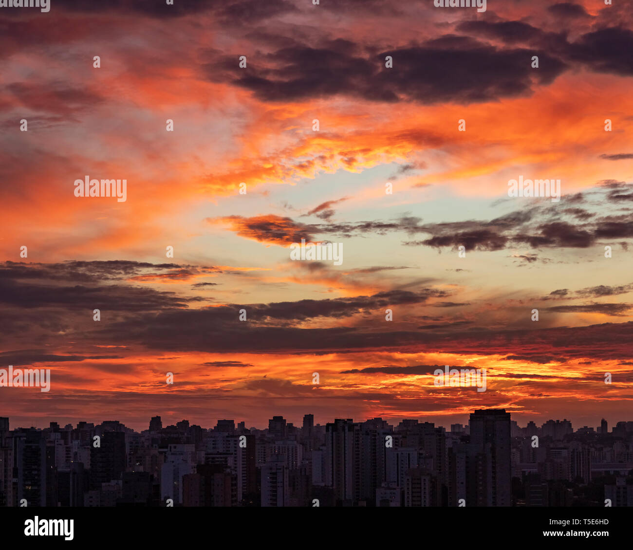 Tramonto in città con lo skyline di industriali e le nuvole, cielo fuoco. Foto Stock