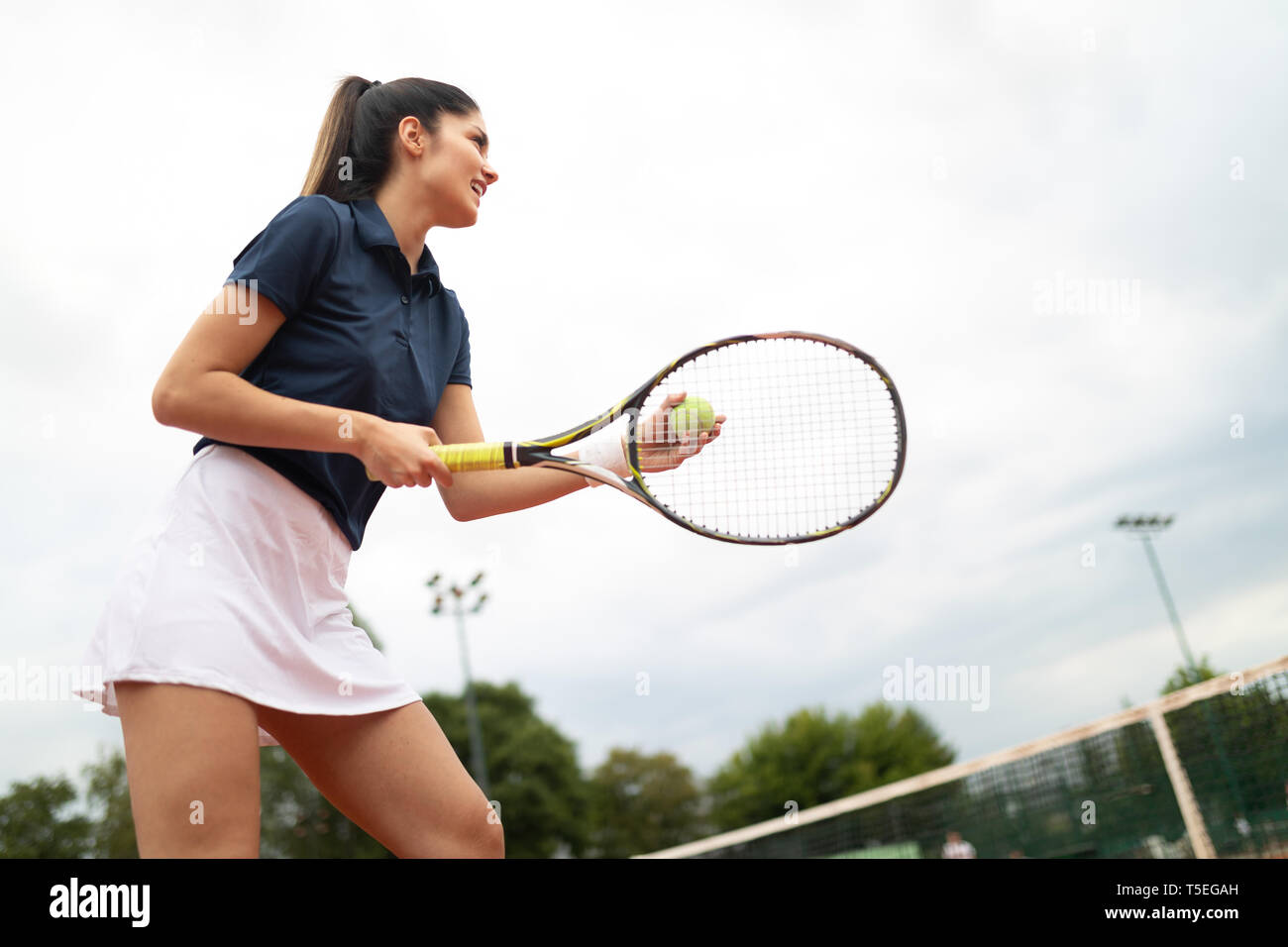 Donna giocatore di tennis sorridente tenendo la racchetta durante il match di tennis Foto Stock