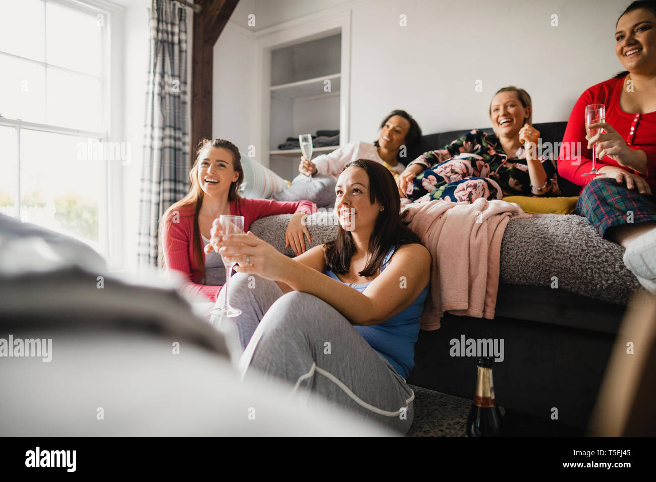 Piccolo gruppo di amici di sesso femminile e rilassante conversazione mentre godendo una serata per ragazze. Essi sono qui seduti in una camera da letto in pigiama. Foto Stock