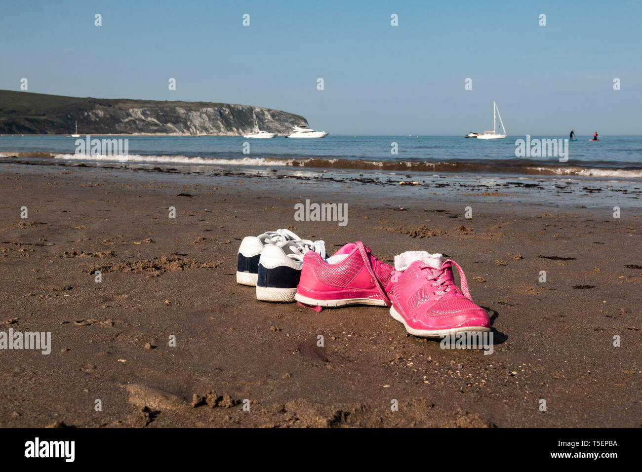 Due paia di scarpe a sinistra sulla sabbia a Swanage beach, REGNO UNITO Foto Stock