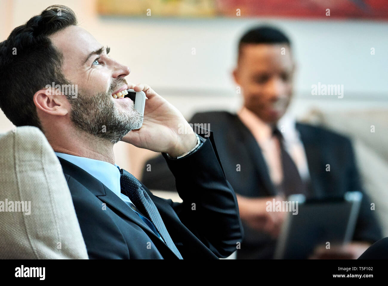 Imprenditore utilizzando smart phone in HALL HOTEL Foto Stock