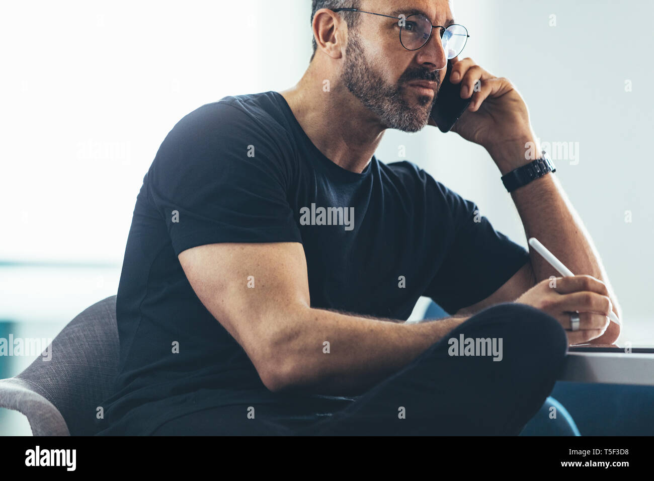 Imprenditore maturo seduto in ufficio e parlando al telefono cellulare. Uomo caucasico facendo una telefonata. Foto Stock