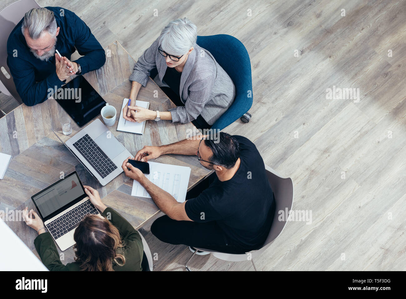 Il team di Business seduti attorno a un tavolo e di parlare su nuove idee. Angolo di alta vista del professionista aziendale avente una riunione in ufficio. Foto Stock