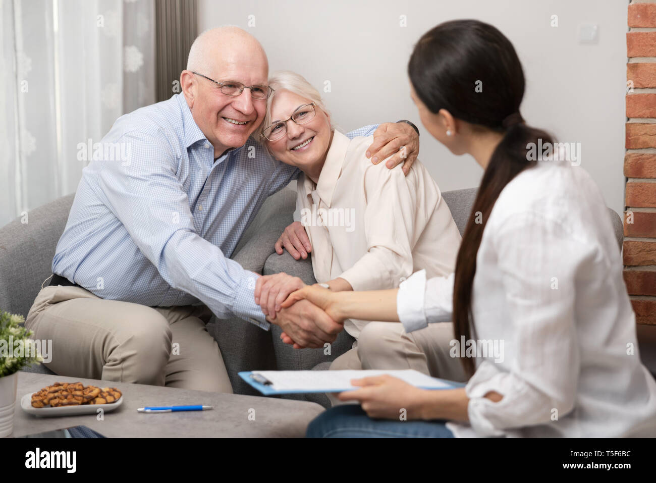 Felice coppia senior pianificare i loro investimenti con il consulente finanziario. Deal Agreement, contratto firmato con il concetto di handshake Foto Stock