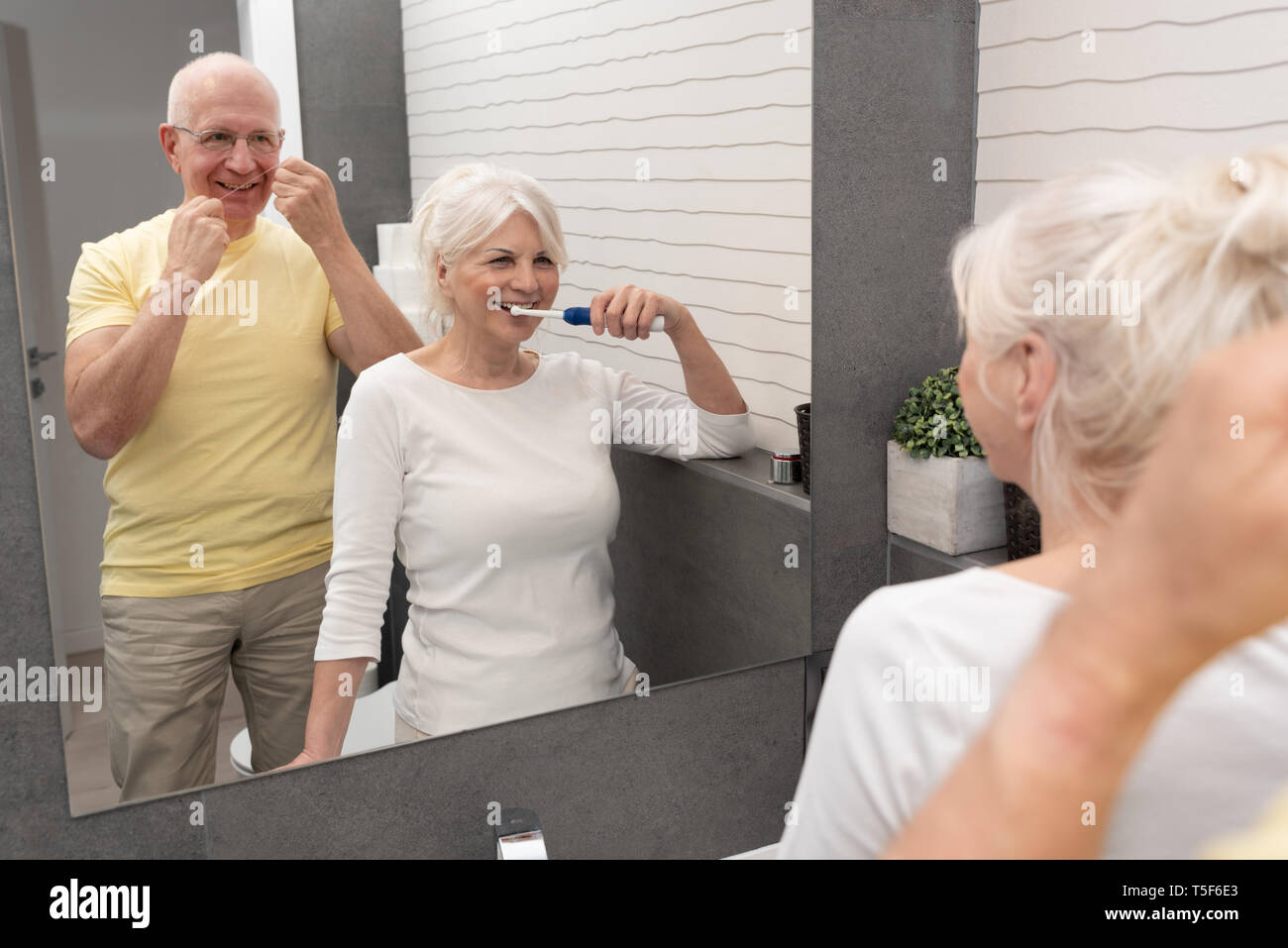 Le persone anziane mediante spazzolatura dei denti e il filo interdentale. La mattina in bagno Foto Stock