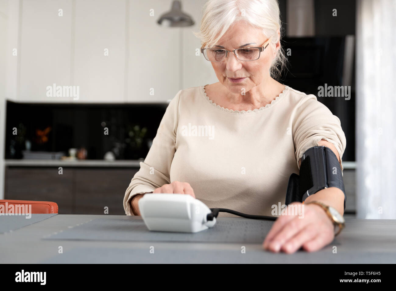 Senior donna adulta la misura della pressione del sangue a casa Foto Stock