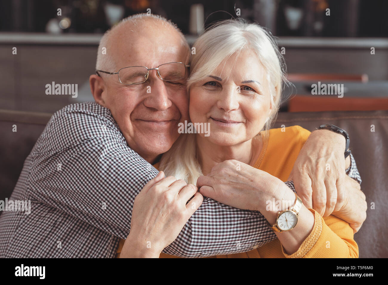 Allegro, romantico coppia senior abbracciando comodamente seduti sul divano di casa Foto Stock