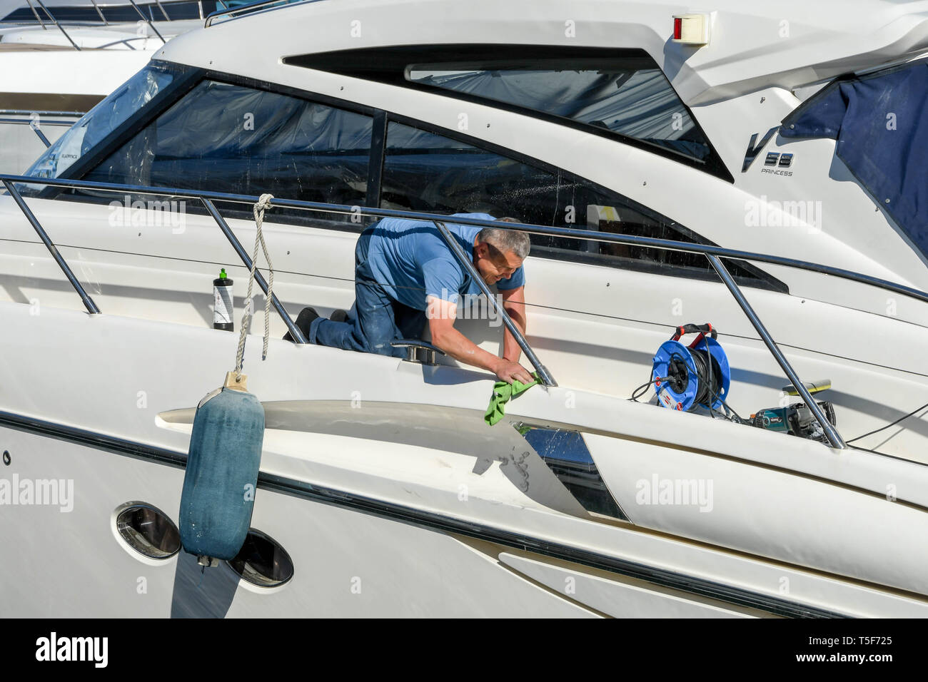 CANNES, Francia - Aprile 2019: Persona la lucidatura della vernice su un superyacht nel porto di Cannes la preparazione per la stagione di charter Foto Stock