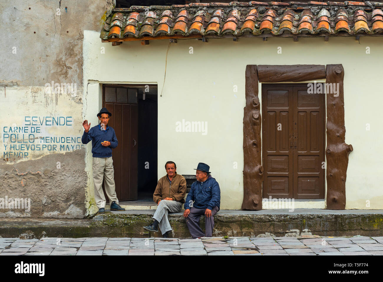 Tre alti uomini parlando davanti della facciata di una casa nella città di Quito, Ecuador. Otavalo è famosa per le sue popolazioni indigene o tessili poncho mercato. Foto Stock