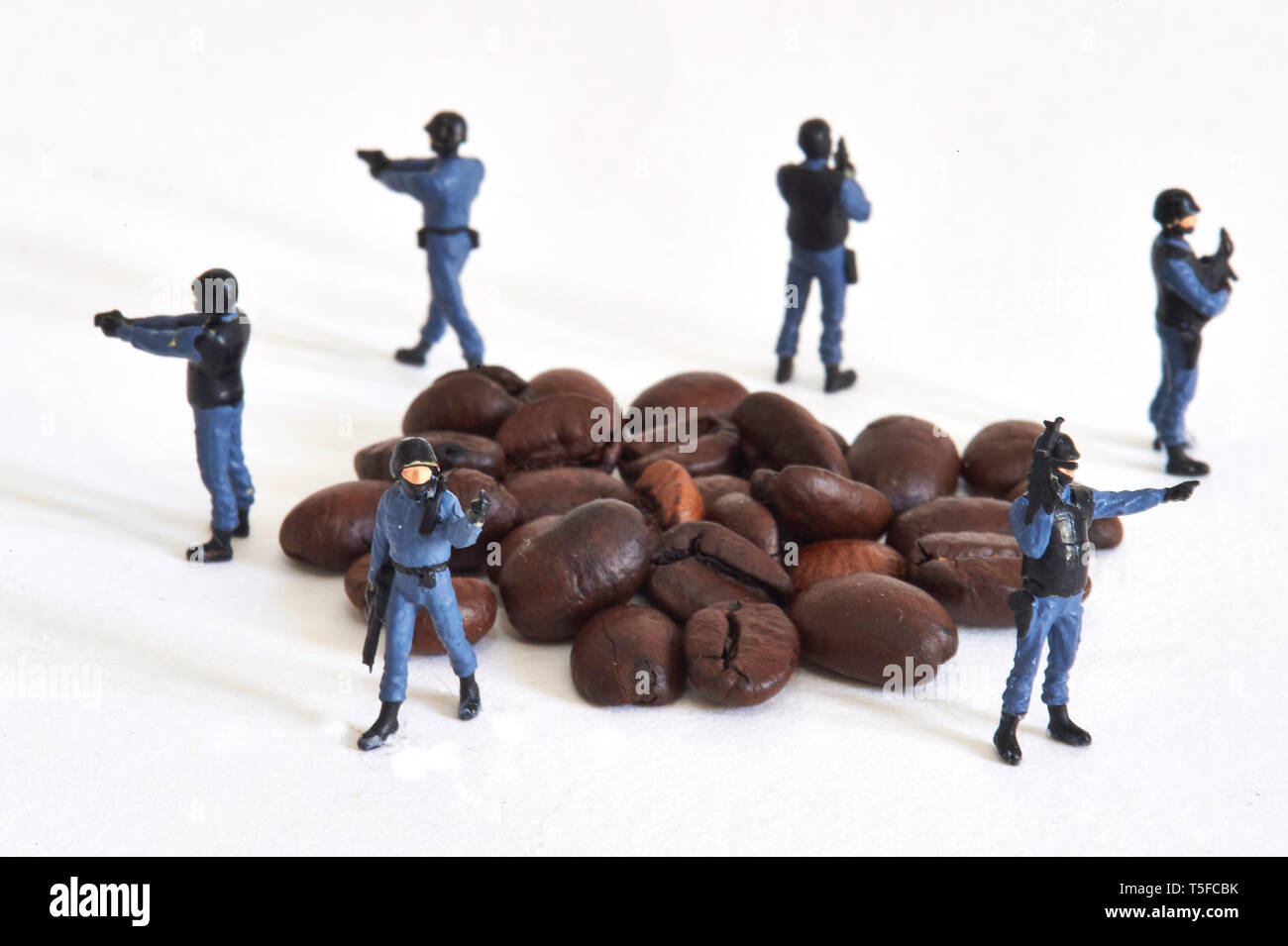 Figurine che rappresentano gli ufficiali di polizia che circonda i chicchi di caffè: protezione e fissaggio globale del mercato del caffè.Caption locale *** Foto Stock
