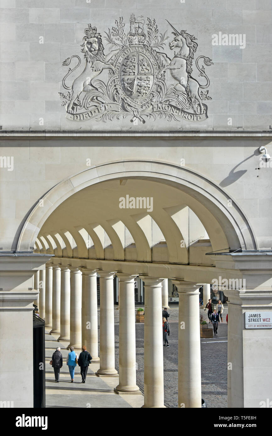I turisti passeggiare sotto lo stemma at Royal Opera House galleria shopping con colonnato facente parte del complesso a Covent Garden Londra Inghilterra REGNO UNITO Foto Stock