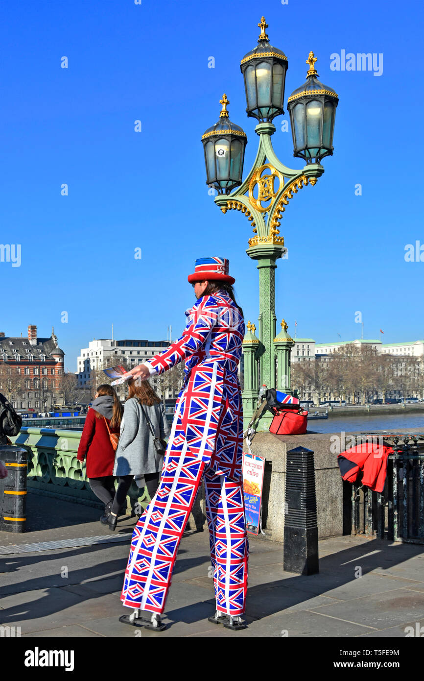L'uomo su palafitte in vestiti stampati con Unione Jack emblema in Londra turismo scena di strada dando il foglietto pubblicità degli alimenti ristorante Londra Inghilterra REGNO UNITO Foto Stock