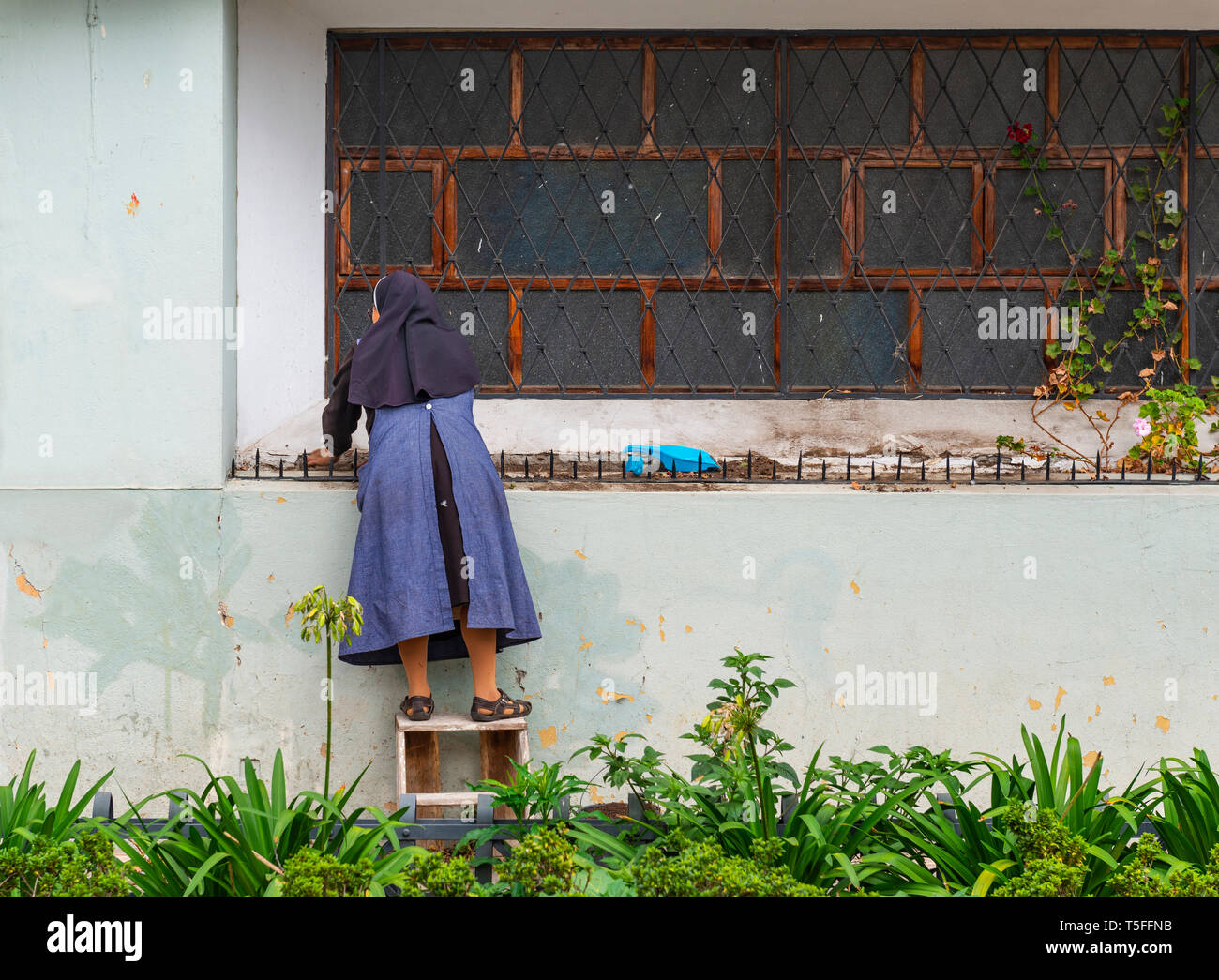 Suora cattolica abito con la pulizia della parte esterna di un convento nel centro della città di Cuenca, Ecuador. Foto Stock