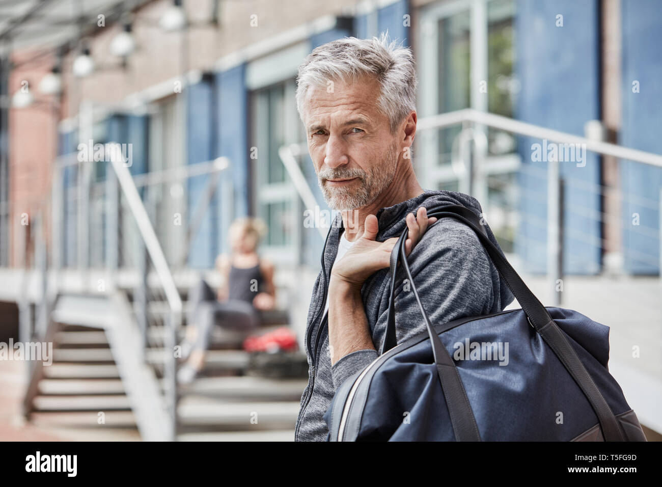 Ritratto di uomo maturo con borsa sportiva di fronte palestra Foto Stock