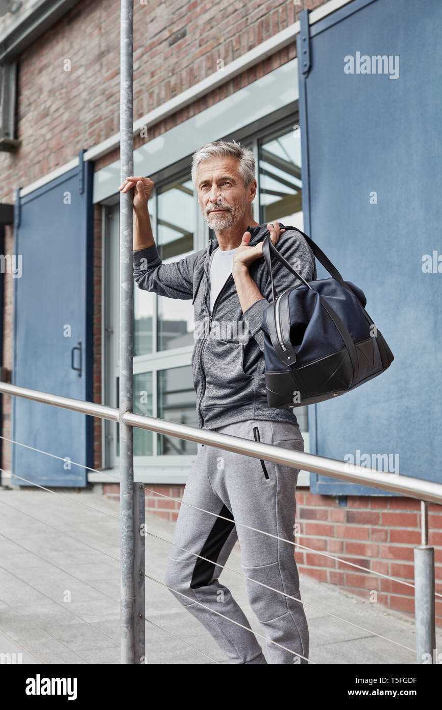 Ritratto di uomo maturo con borsa sportiva in piedi nella parte anteriore della palestra Foto Stock