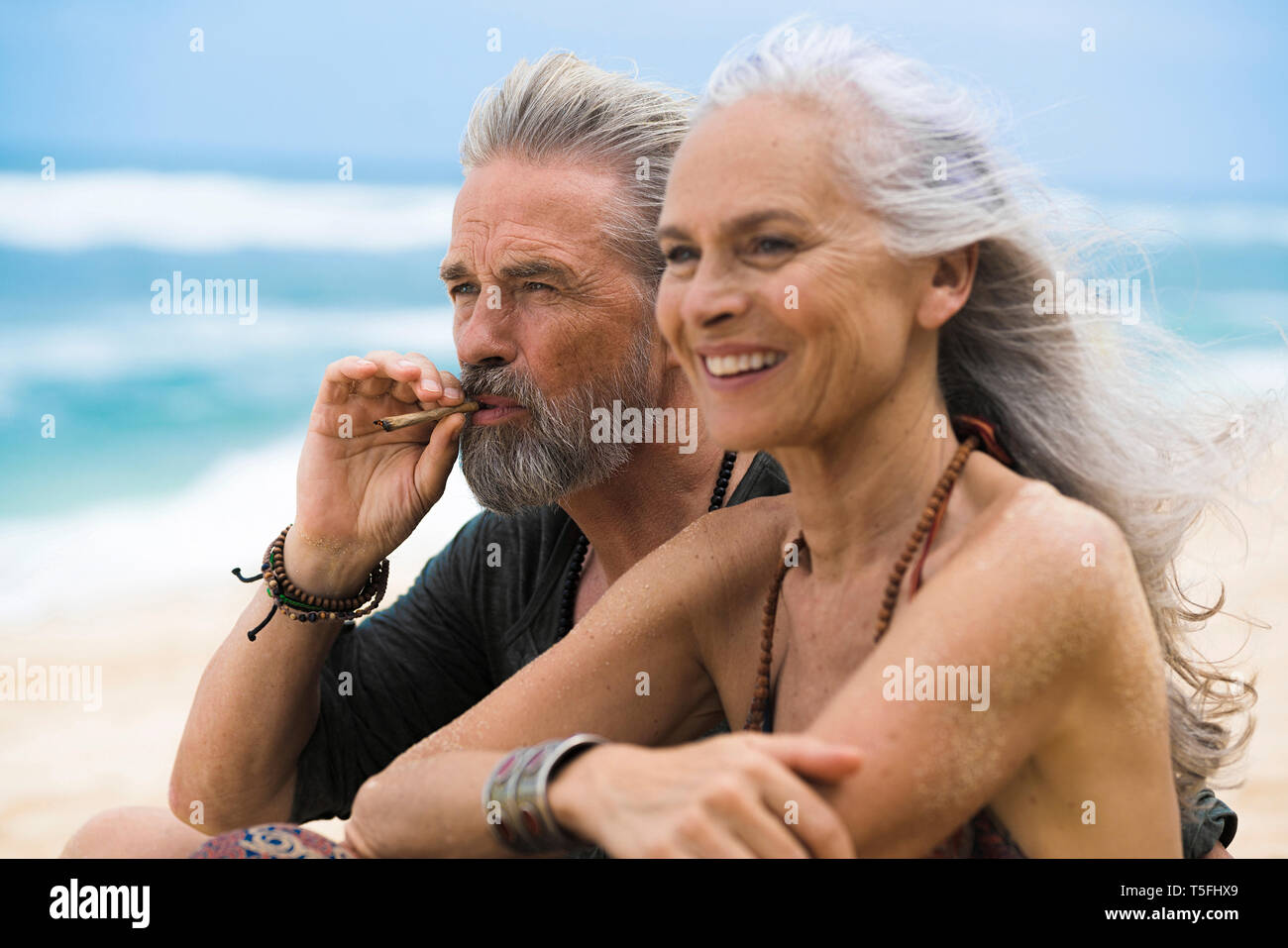 Senior coppia hippie insieme rilassante sulla spiaggia Foto Stock