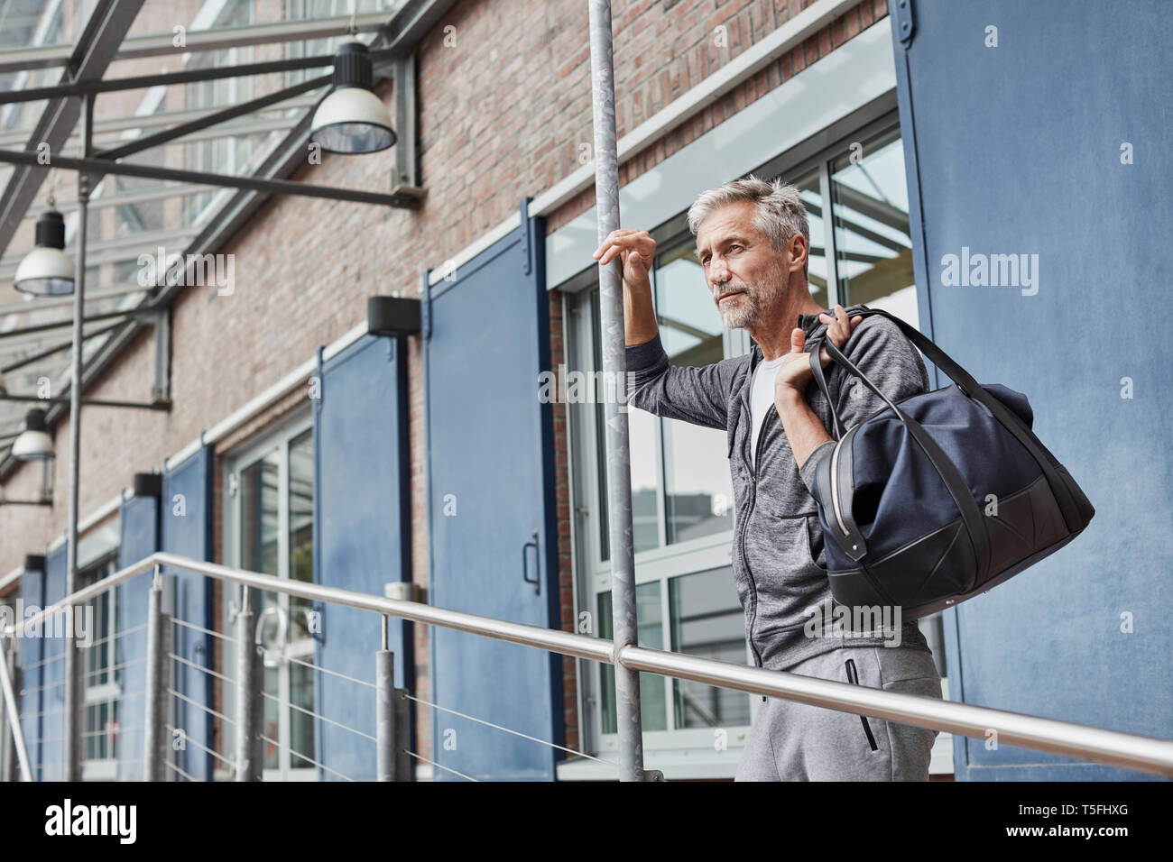 Uomo maturo con borsa sportiva in piedi nella parte anteriore della palestra Foto Stock