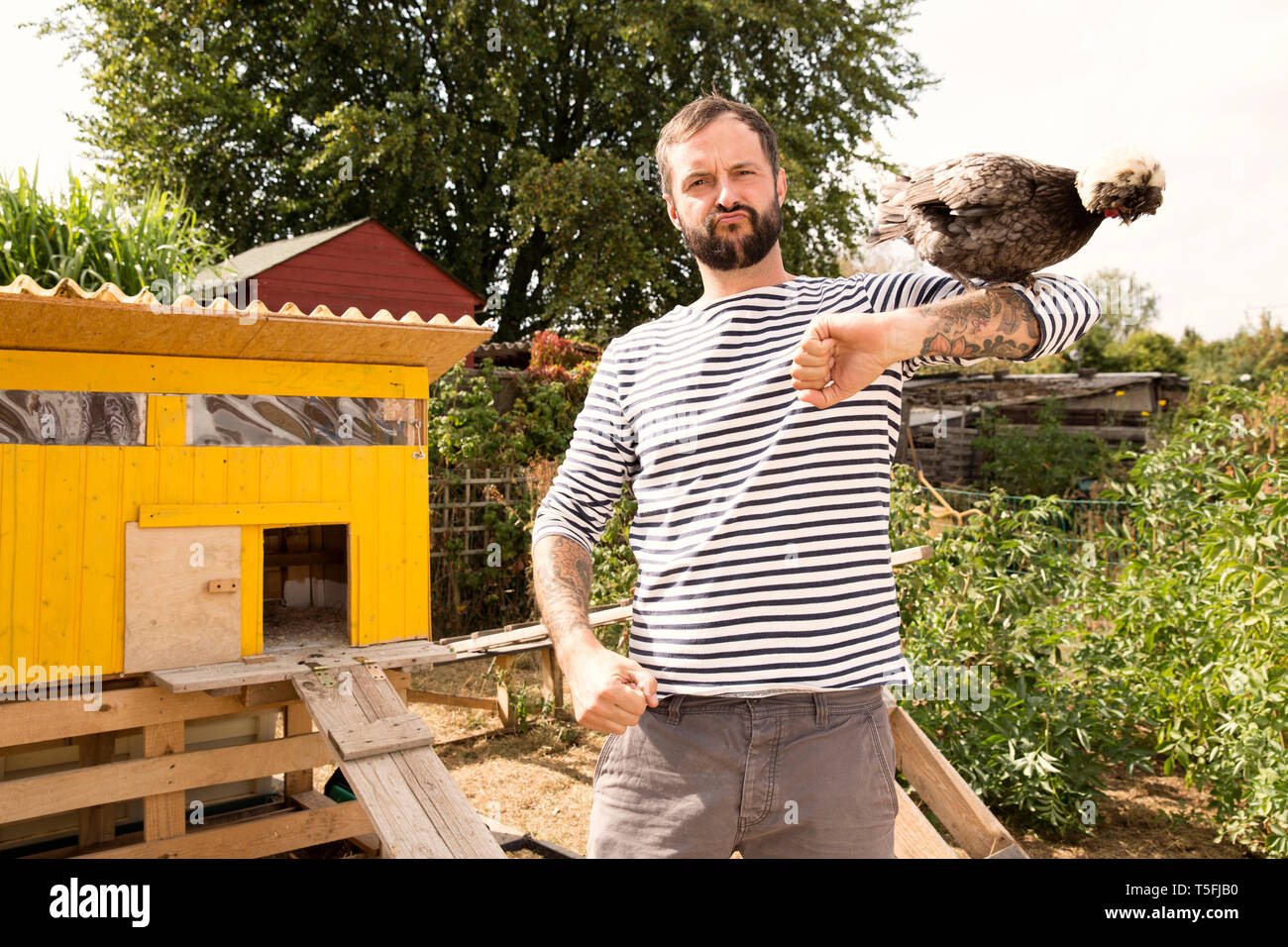 Ritratto di uomo con pollo polacco a chickenhouse in giardino Foto Stock