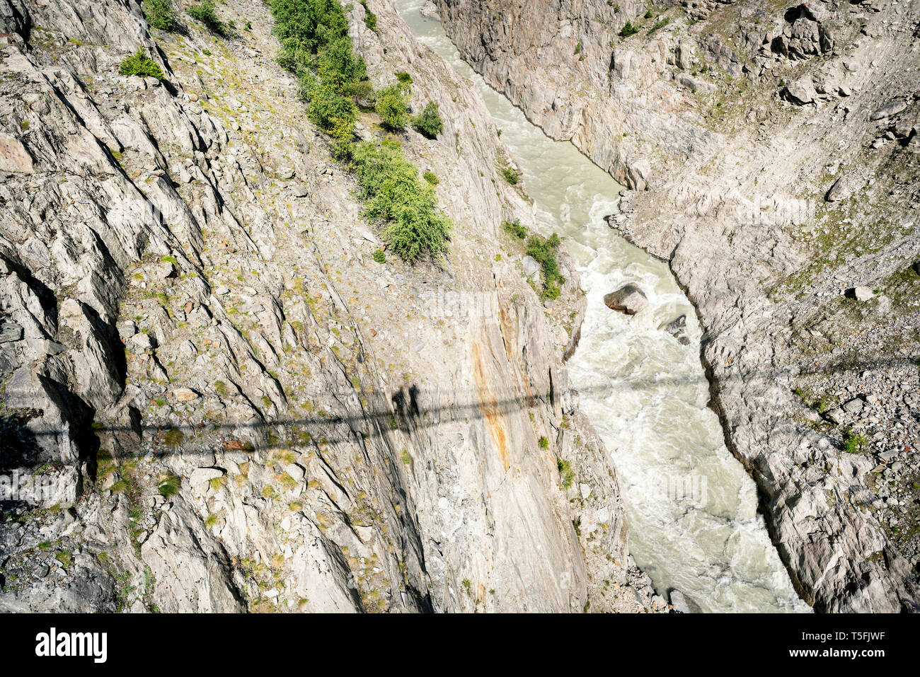 La Svizzera, Vallese, le ombre di due persone su un ponte oscillante sopra una gola Foto Stock