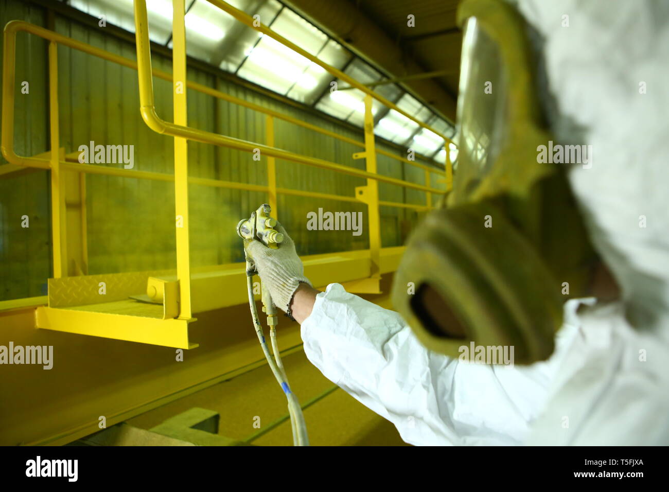 Verniciatura industriale parti. Il pittore dipinge l'elemento ferro in giallo. Foto Stock