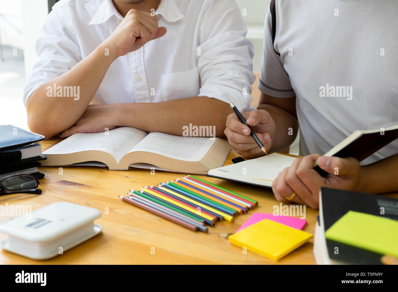 Gli studenti amico aiuta l insegnamento e l apprendimento oggetto ulteriori nella libreria. Il concetto di istruzione. Foto Stock