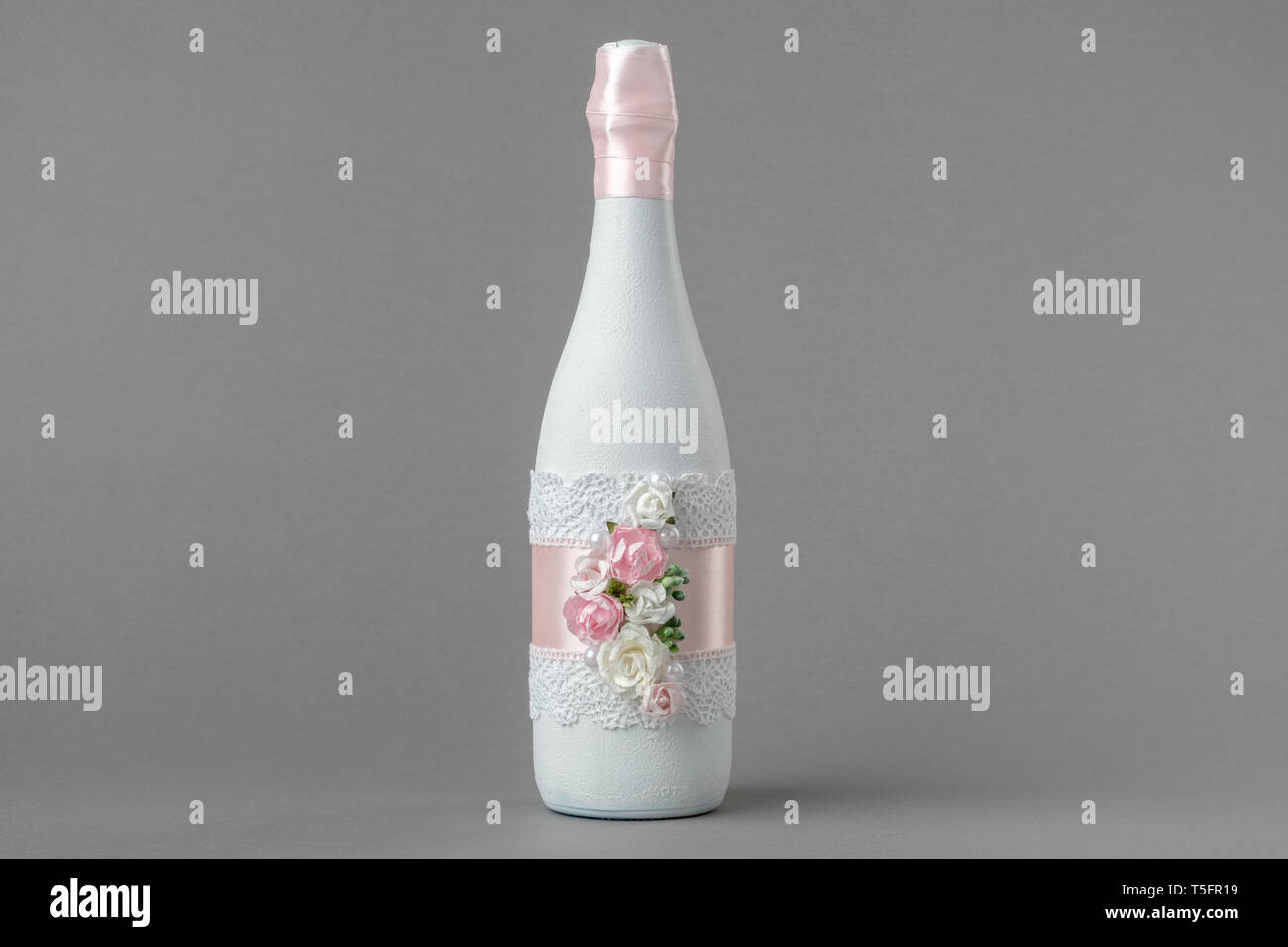 Nozze bottiglia di champagne decorate con rose, pizzo e nastro. Foto Stock