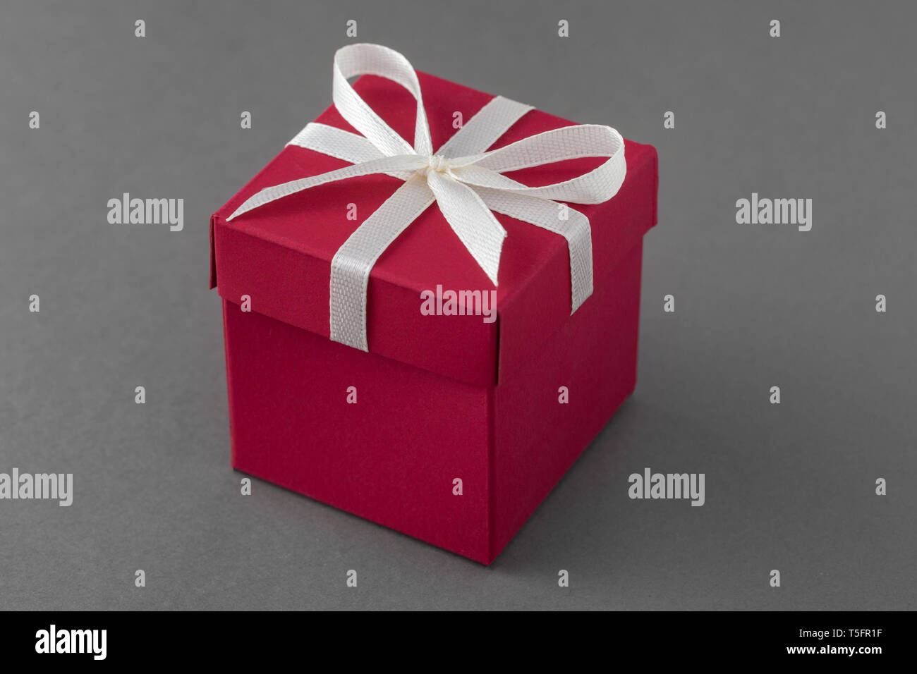 Red elegante confezione regalo con nastro su sfondo grigio. Foto Stock