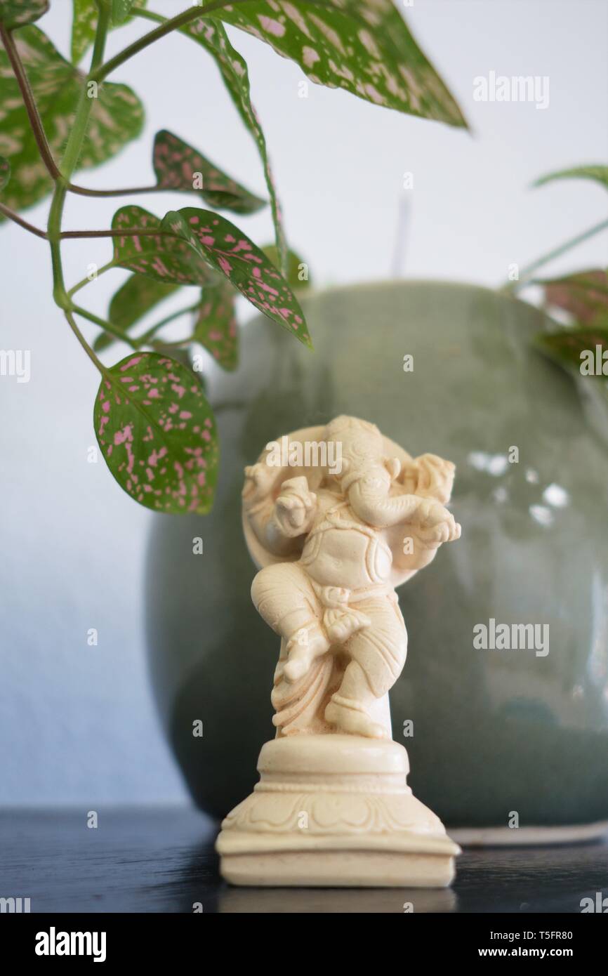 Un piccolo Ganesha figurina, accanto a una pianta in vaso su un ripiano. Foto Stock