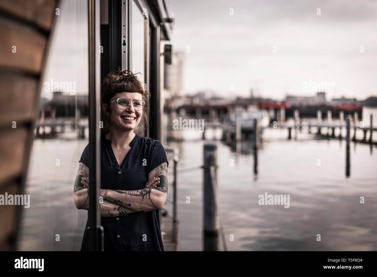 Donna appoggiata nella finestra di una casa galleggiante, prendendo una pausa Foto Stock