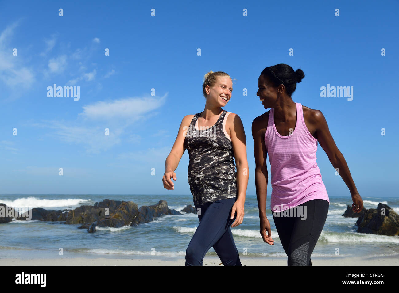 Due donne felice di camminare sulla spiaggia Foto Stock