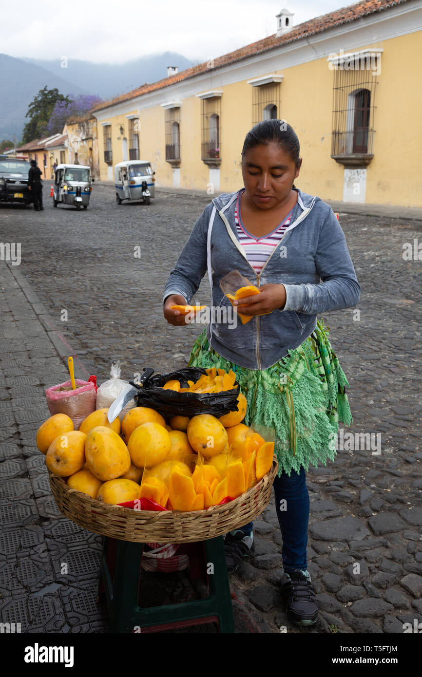 Guatemala America Latina - una donna guatemalteca per la vendita di frutta da una bancarella di strada, Antigua, Guatemala America Centrale Foto Stock
