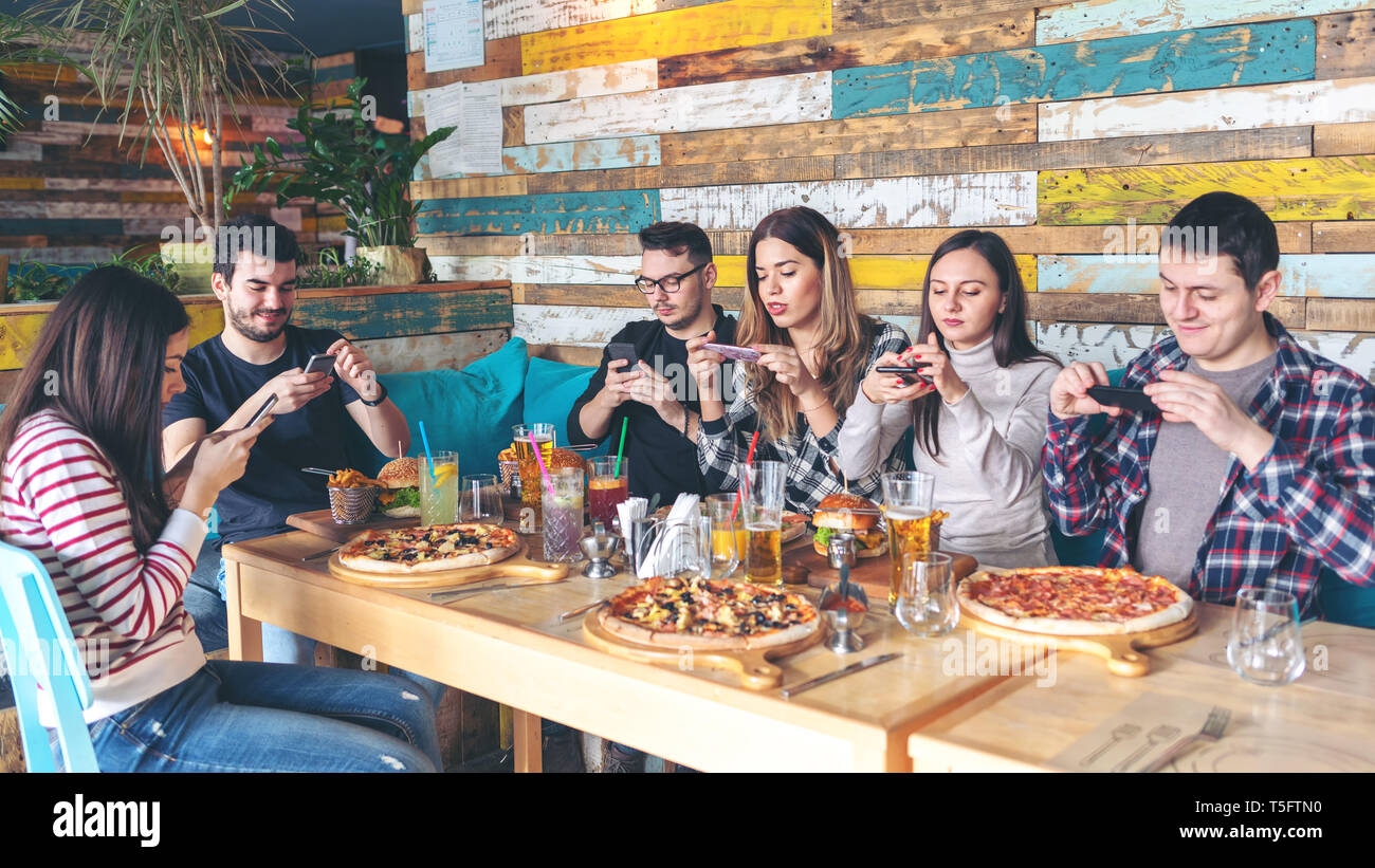 Social media addiction concetto con i giovani a fotografare il cibo al pub moderno Foto Stock