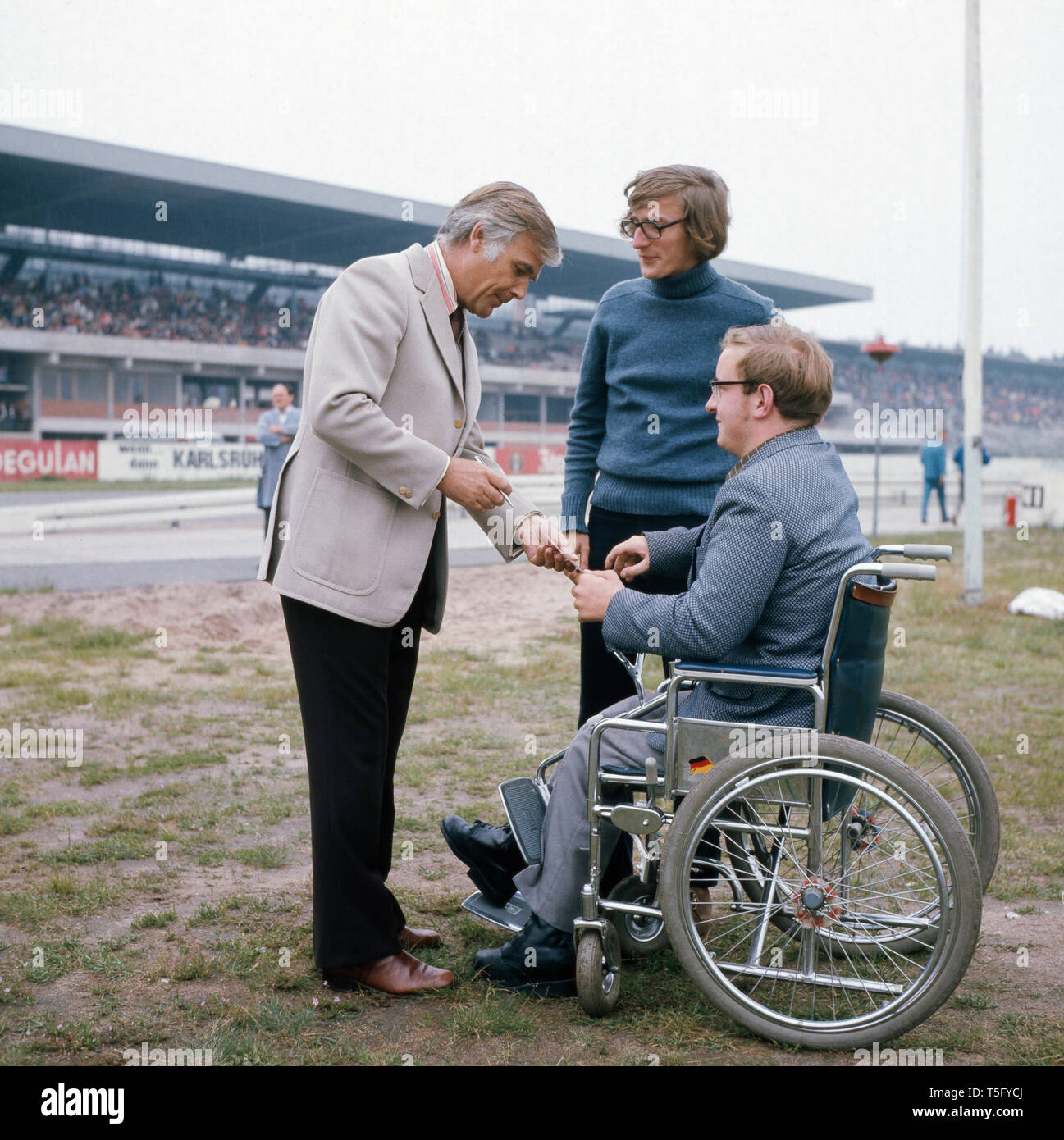 Fuchsberger begrüßt einen ventola Rollstuhl im abseits der Rennbahn, ca 1970. Fuchsberger accoglie un ventilatore in una sedia a rotelle fuori pista, ca 1970 Foto Stock