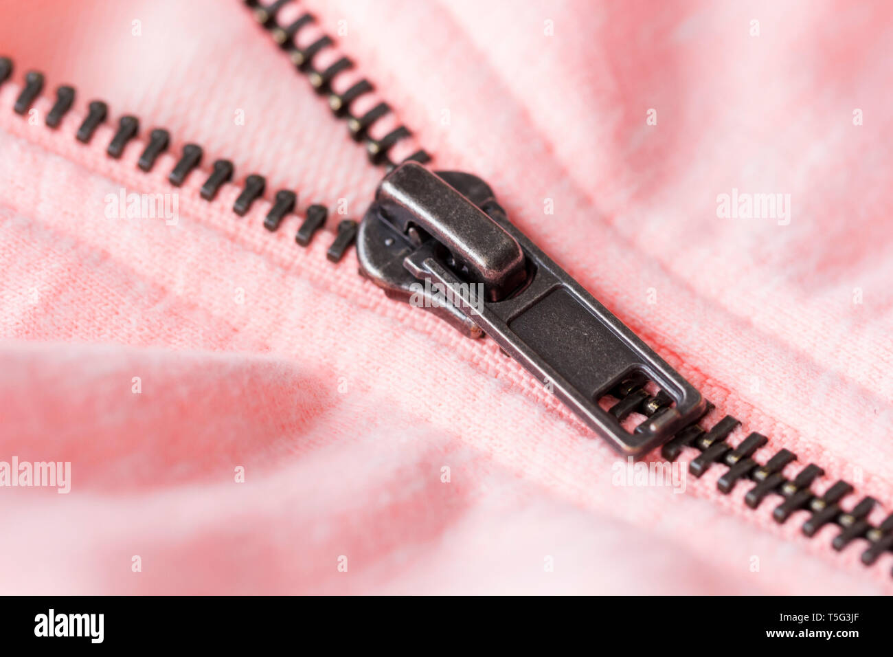 Vista ravvicinata di una zip su una camicia rosa Foto Stock