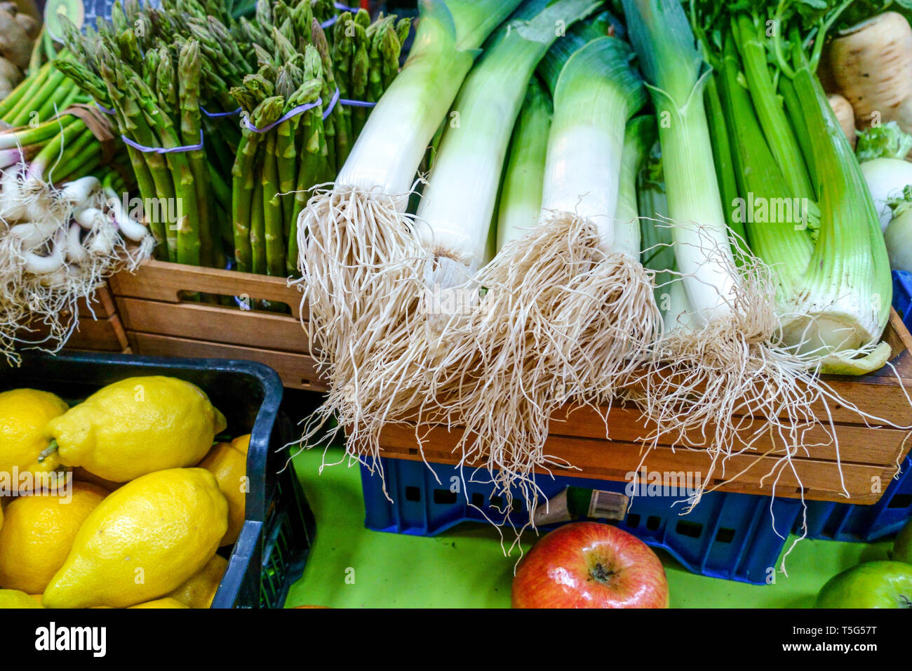 Porri freschi con radici, asparagi verdi, sedano e limoni in mostra in un mercato di verdure a Valencia, Spagna Foto Stock