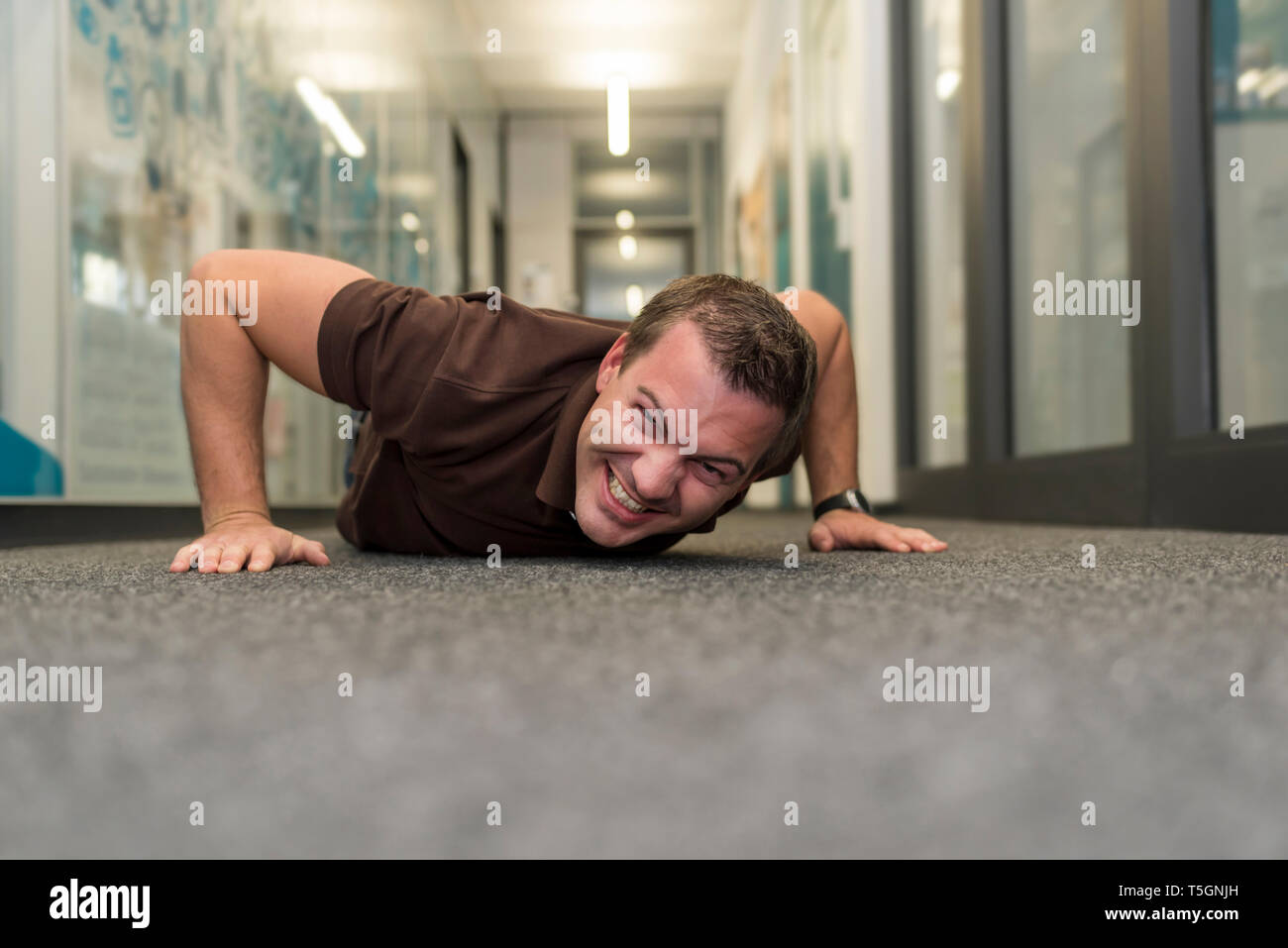 Imprenditore facendo push-up sul pavimento per ufficio Foto Stock