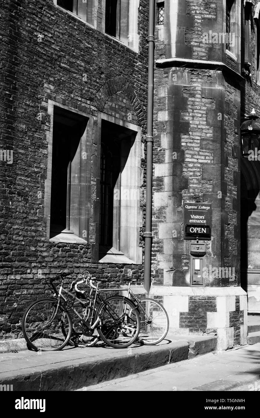 In bianco e nero di scena Pushbikes parcheggiata fuori l'ingresso del Queens' College, Cambridge, Cambridgeshire, Inghilterra Foto Stock