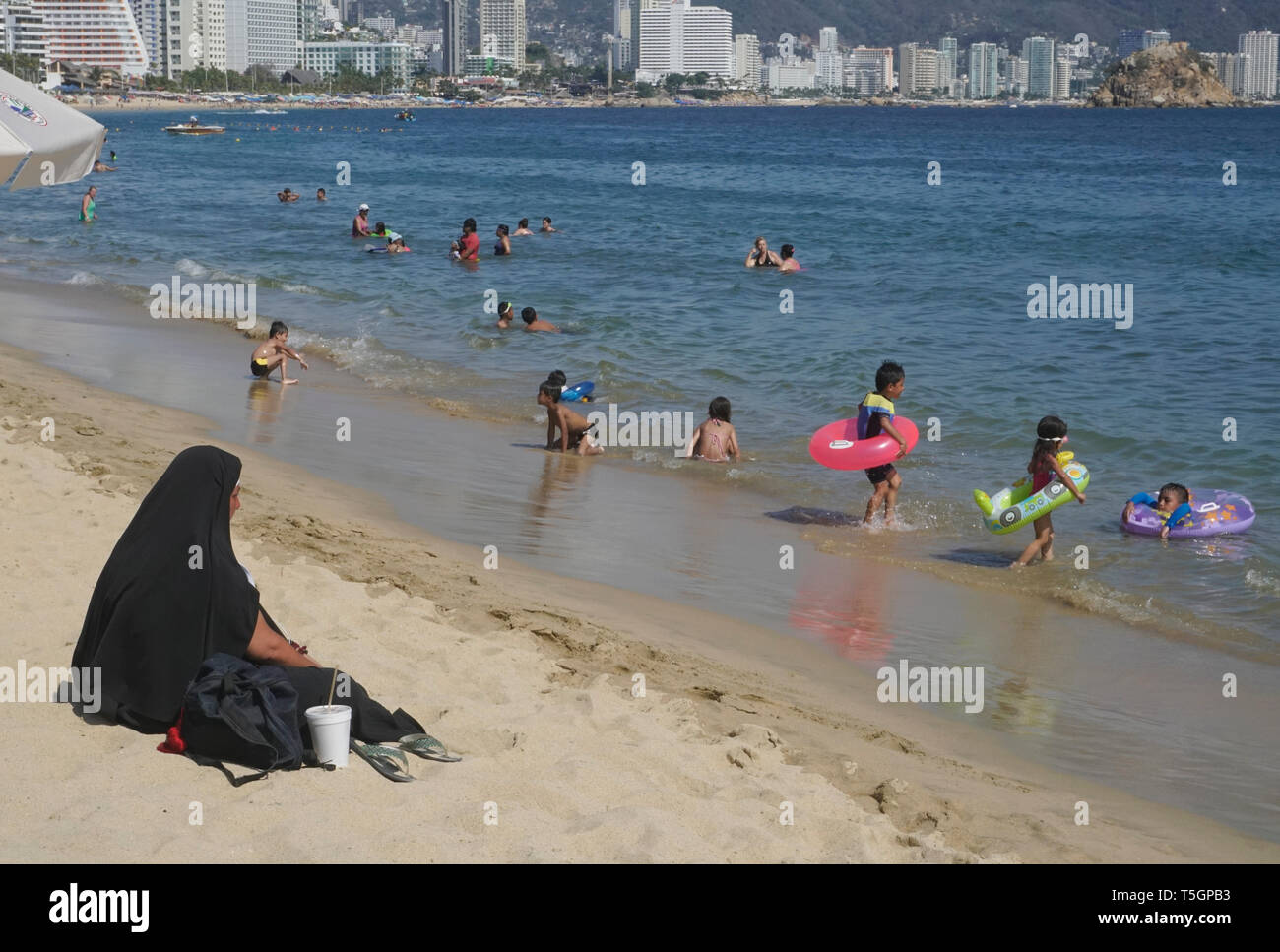 La donna a caldo abbigliamento religiosi presso la spiaggia di Acapulco, Messico Foto Stock