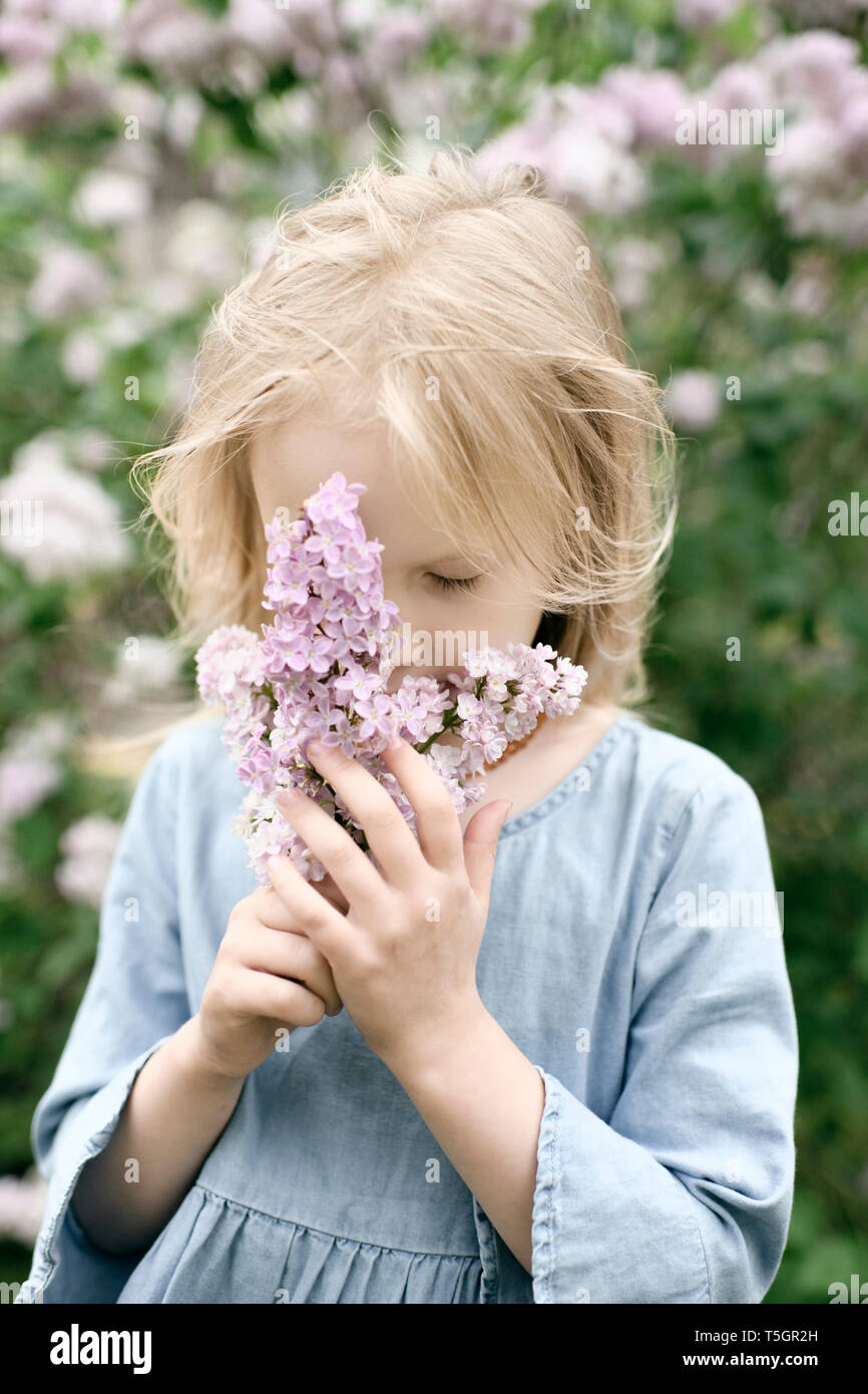 Ritratto di ragazza sorridente con fiori lilla, annusando Foto Stock