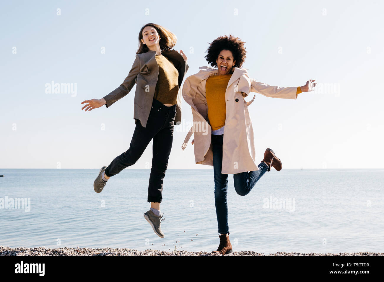 Due amici felice salto sulla spiaggia godendosi il tempo libero Foto Stock