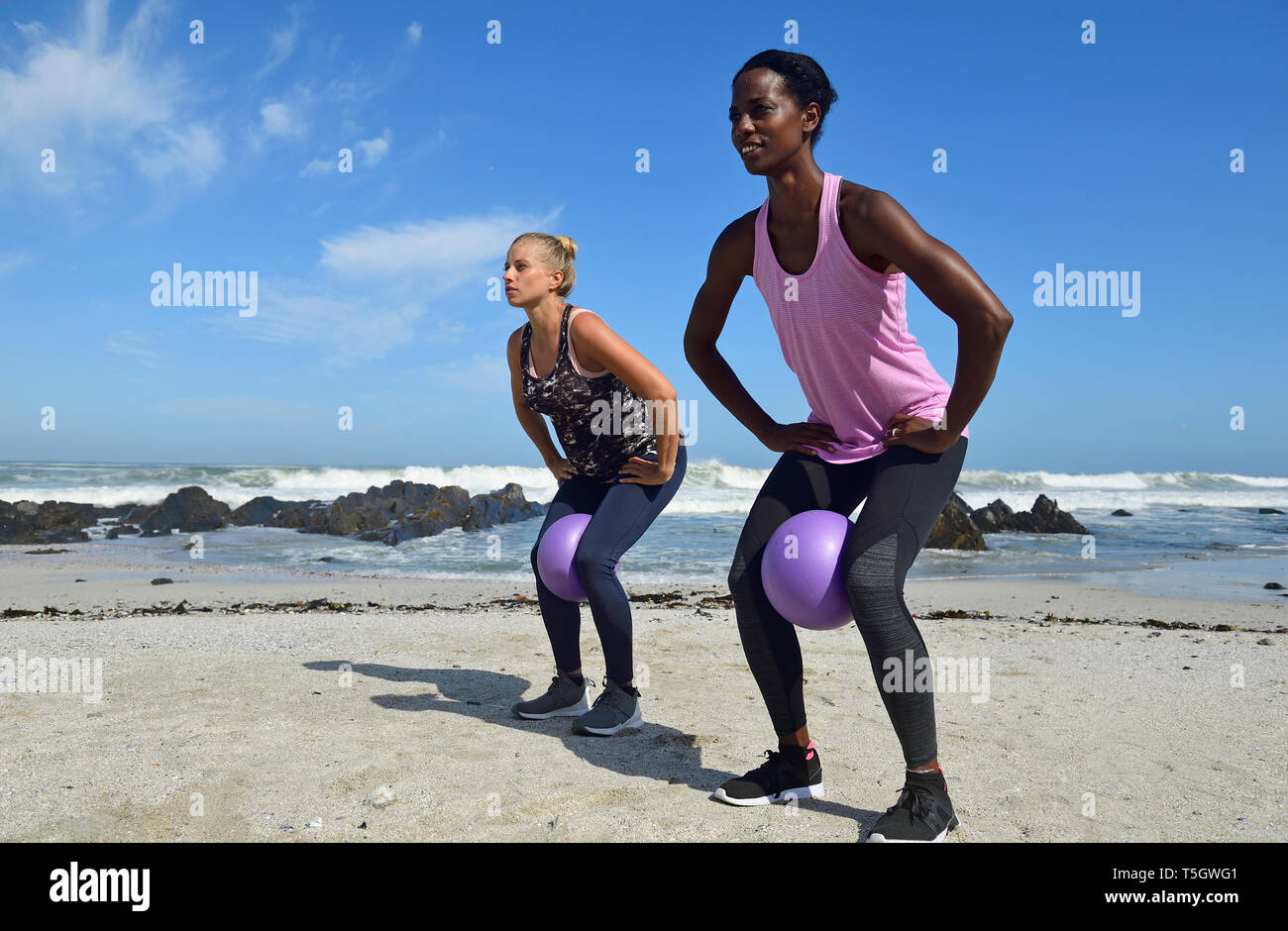 Due donne facendo esercizi di fitness con sfera sulla spiaggia Foto Stock