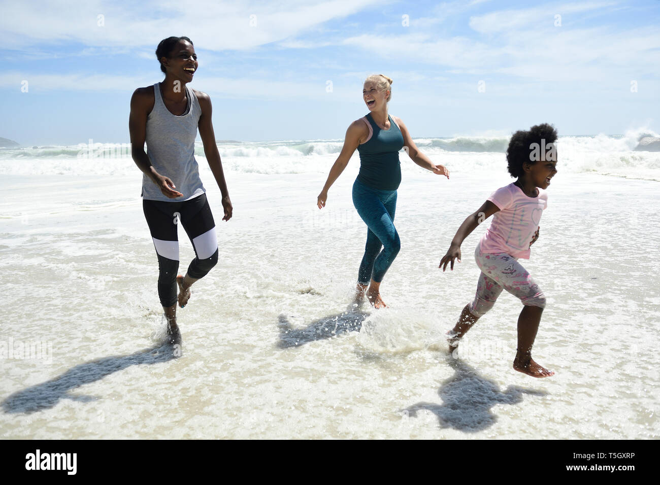 Madre e figlia e amico divertendosi in surf sulla spiaggia Foto Stock
