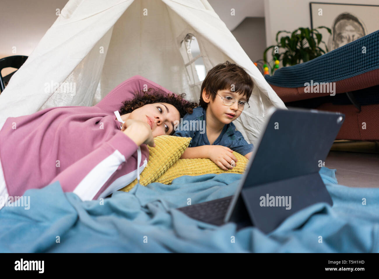 Madre e figlio giacente in gioco tenda, guardare film su tablet Foto Stock
